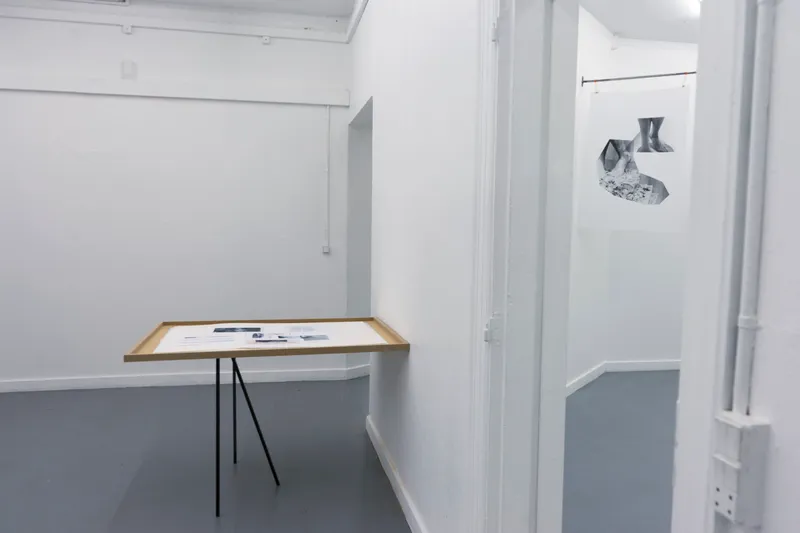 A wooden display table on thin legs with documents, in a white room