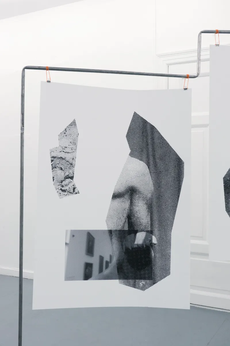 Close-up of a print hanging from a steel frame: halftone fragments of a sculpted body