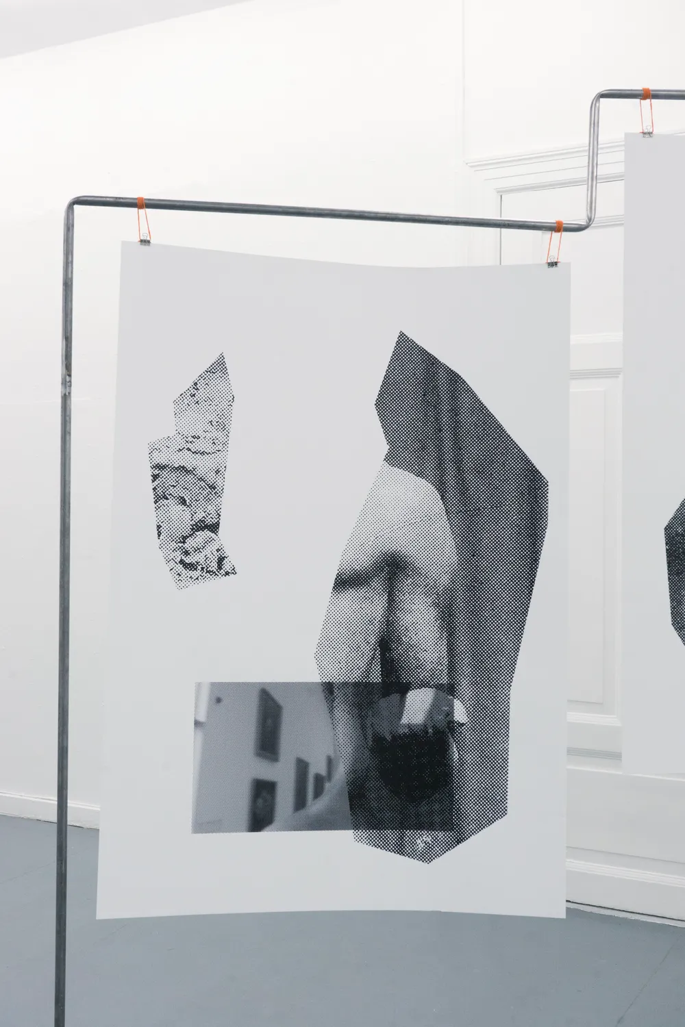 Close-up of a print hanging from a steel frame: halftone fragments of a sculpted body