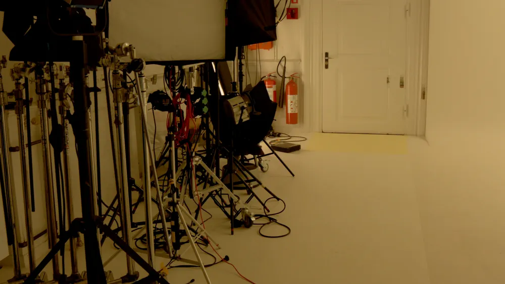 A photo studio with light stands, cables and a white wall