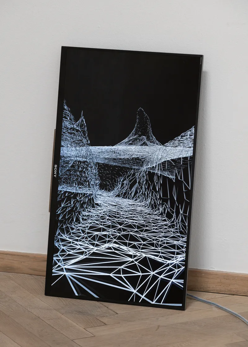 A tall screen leaning against the wall showing a white wireframe landscape